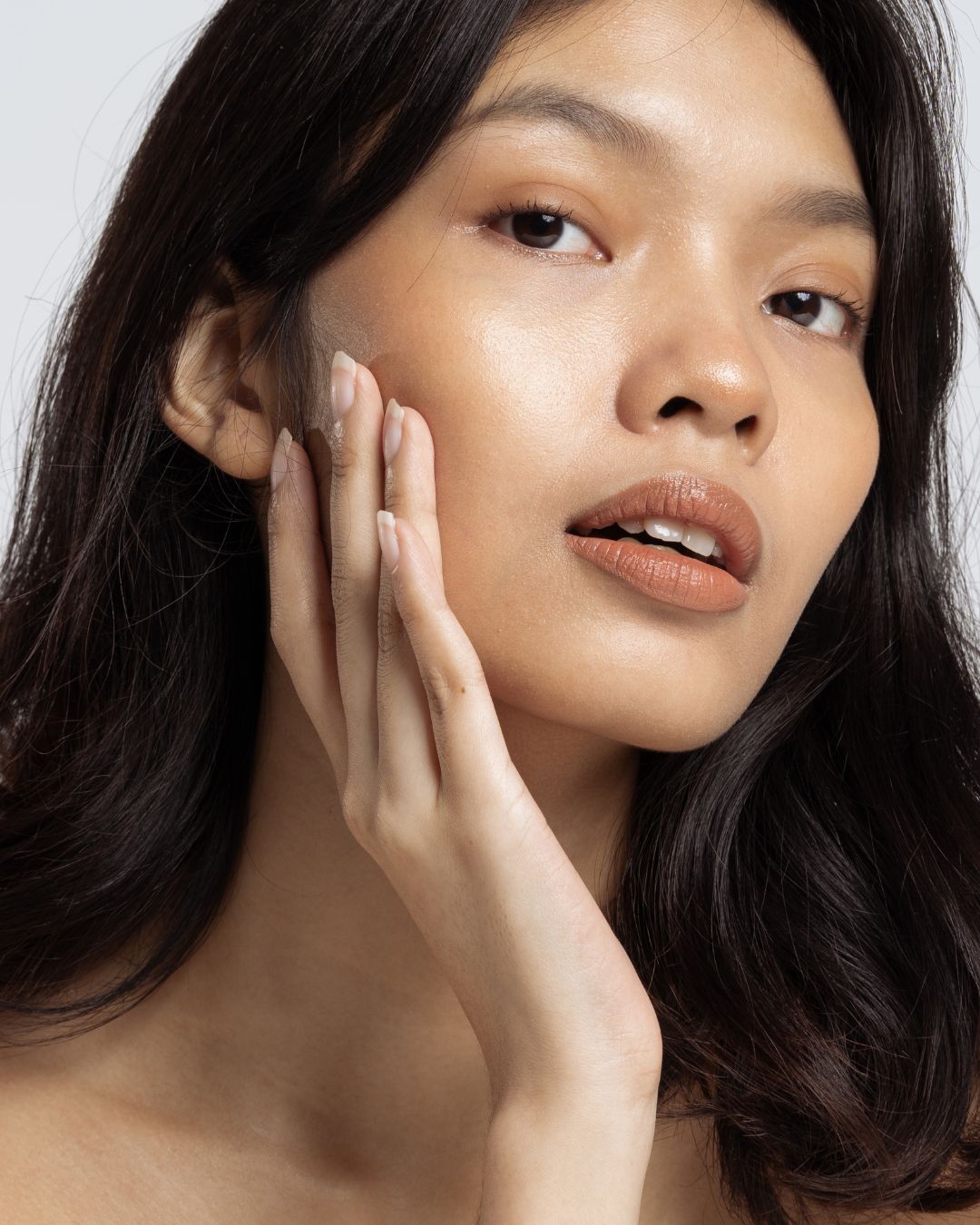 Femme au teint lumineux touchant son visage après un soin Lazen